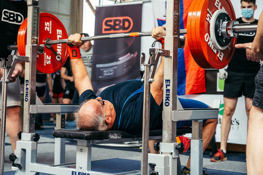 A powerlifter bench pressing a loaded barbell at a competition