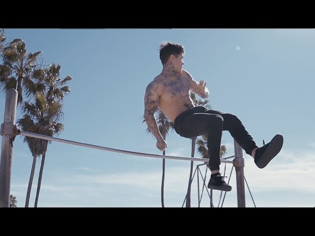 Chris Heria demonstrating an advanced bodyweight bar skill outdoors at Venice Beach