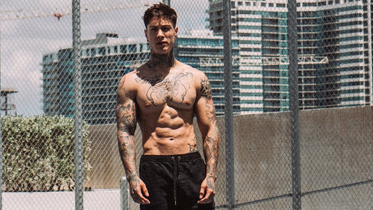 Chris Heria shirtless in an outdoor gym showing a lean muscular physique and defined torso