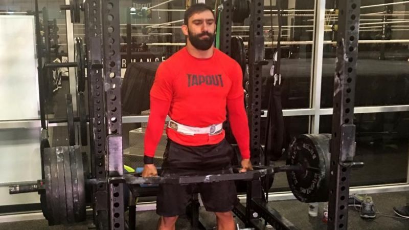 Eric Bugenhagen standing with a heavily loaded barbell inside a weight-training facility