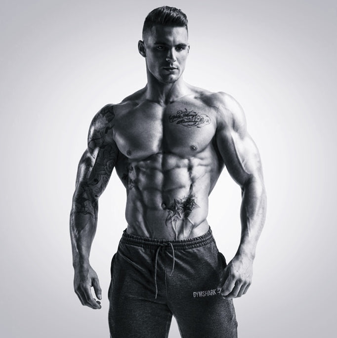 Ross Dickerson posing shirtless in black-and-white fitness photography, showing developed chest, shoulders and abdominal definition