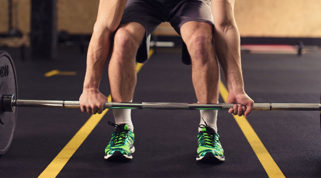 A lifter grasping a barbell with both hands while setting up a heavy deadlift