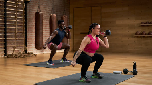 Two adults performing dumbbell squat training in a fitness studio