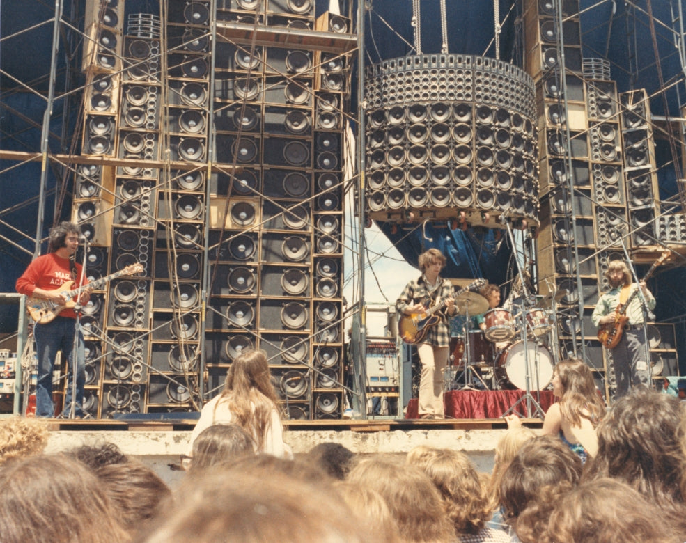 Grateful Dead playing a live concert with the towering Wall of Sound speaker system and an outdoor crowd