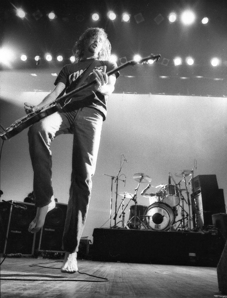 Krist Novoselic jumping with his bass during a high-energy Nirvana performance