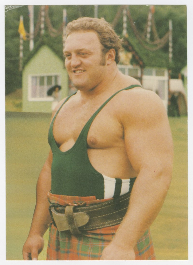 Vintage photograph of Bill Kazmaier wearing a green strongman singlet outdoors, showing his powerful physique