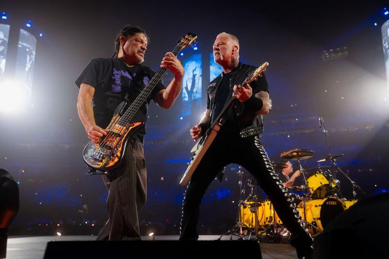 James Hetfield and Robert Trujillo playing guitar and bass with Lars Ulrich on drums during a Metallica stadium performance