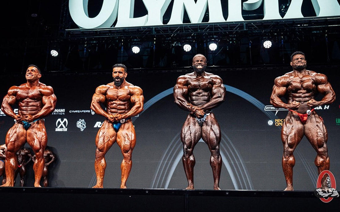 Male physique competitors posing in a bodybuilding stage lineup at an illustrative competition, not the Bradford 2026 show