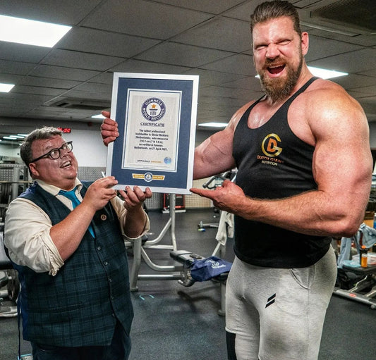 Olivier Richters the Dutch Giant flexing his arms outdoors in a white shirt