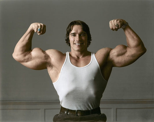 Arnold Schwarzenegger flexing both biceps in a white tank top