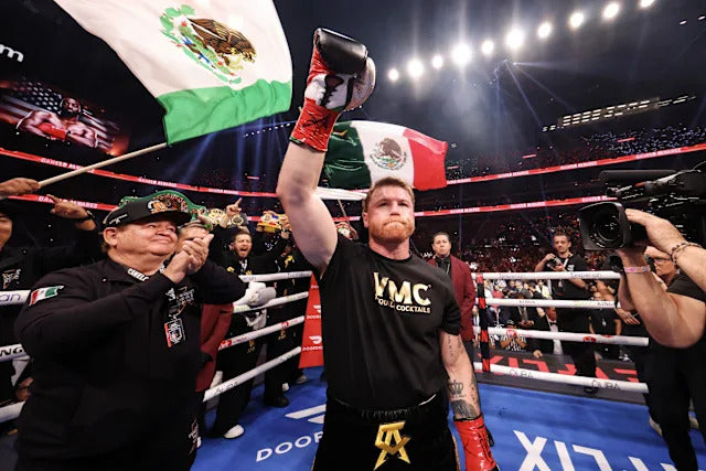 Canelo Alvarez raises his glove with a Mexican flag behind him