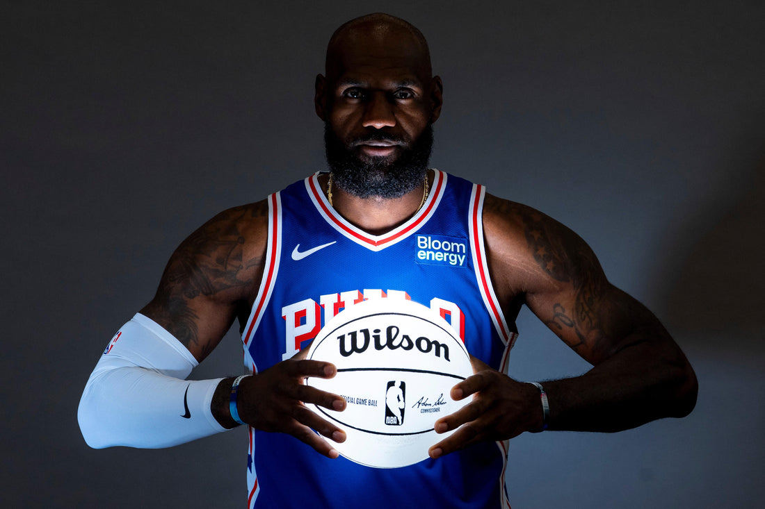 LeBron James holds a basketball wearing a blue Philadelphia 76ers jersey at September 2026 media day