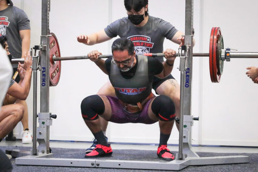 Athlete performing a loaded lower-body squat in a gym, illustrating progressive hip and knee strength training