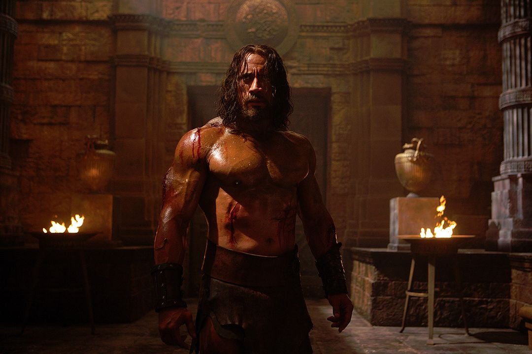 Dwayne Johnson as Hercules shirtless in a torchlit stone temple