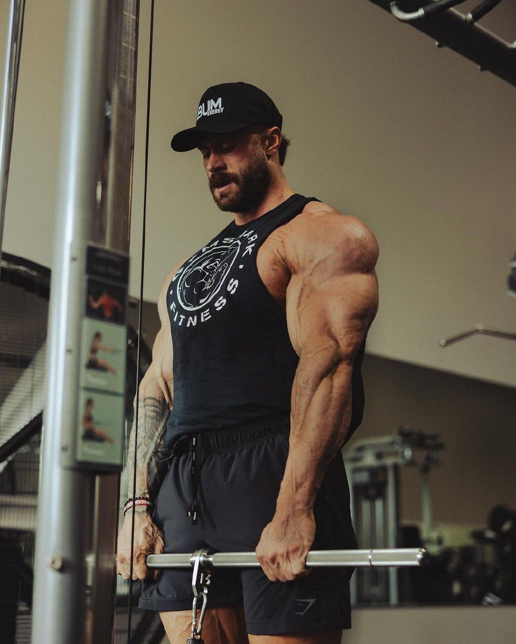 Chris Bumstead wearing a bodybuilding tank top with muscular arms and shoulders visible