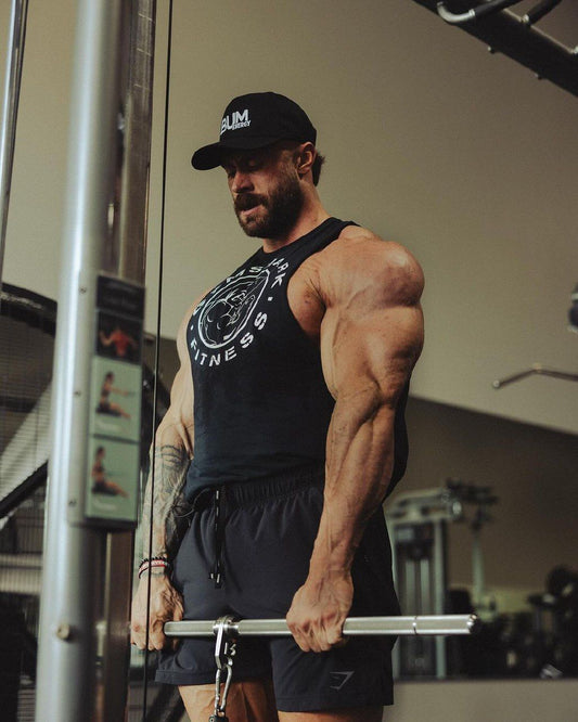 Chris Bumstead wearing a bodybuilding tank top with muscular arms and shoulders visible