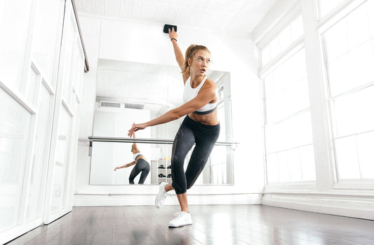 Karlie Kloss extending one arm in a bright dance studio during an adidas athletic training session
