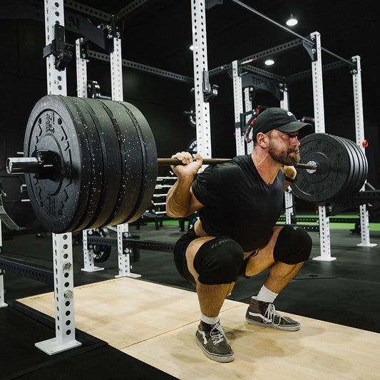 Athlete performing a controlled heavy barbell back squat in a power rack