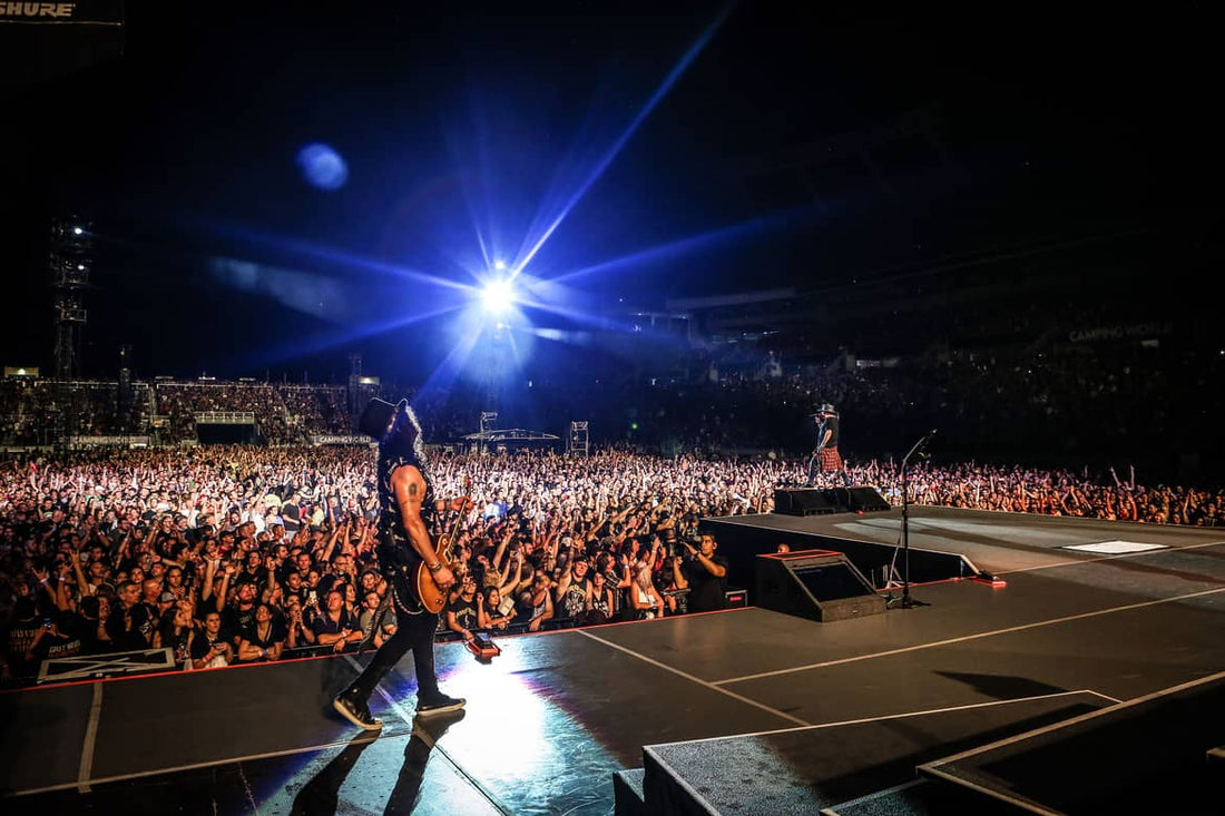 Rock concert crowd and guitarist under bright stage lights, representing decades of high-energy rock music