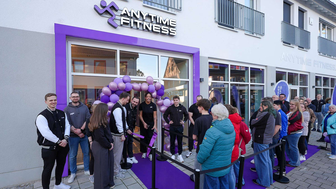 Staff and members gathered at a newly opened Anytime Fitness gym with purple balloons and branded entrance
