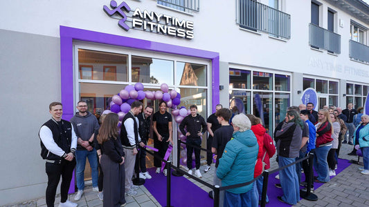 Staff and members gathered at a newly opened Anytime Fitness gym with purple balloons and branded entrance