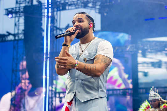 Drake performing into a microphone in a light blue vest onstage at Wireless Festival