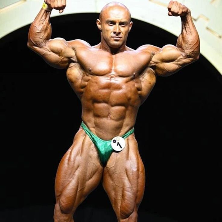 Radoslav Angelov posing on a bodybuilding stage with a deeply conditioned 212 physique