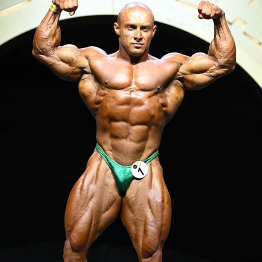 Radoslav Angelov posing on a bodybuilding stage with a deeply conditioned 212 physique