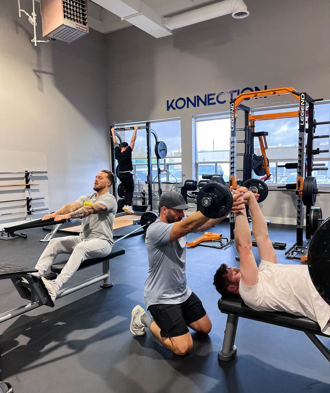 Multiple athletes training upper-body strength with bench press, rowing and pull-ups in a gym