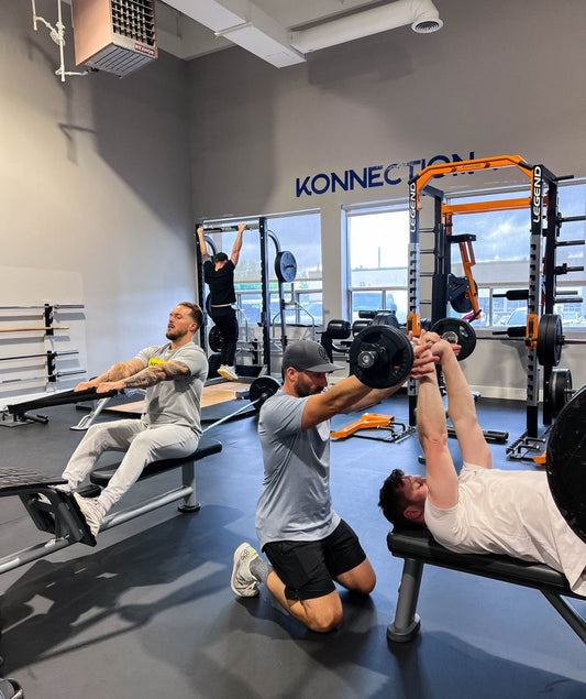 Multiple athletes training upper-body strength with bench press, rowing and pull-ups in a gym