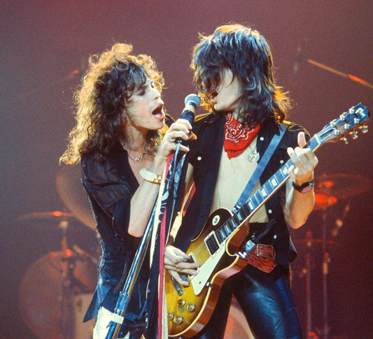 Steven Tyler and Joe Perry of Aerosmith performing together onstage with a microphone and guitar