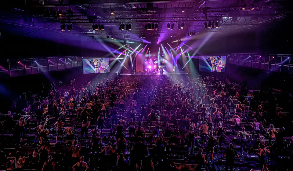 Les Mills Live Barcelona 2026 fitness instructors on illuminated stage with large participating crowd