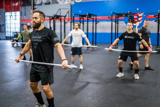 Strength athletes warming up with light bars before resistance training