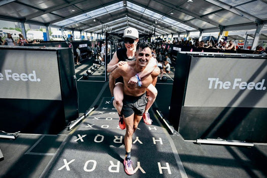 Two HYROX blind-date mixed doubles athletes celebrating together after their race