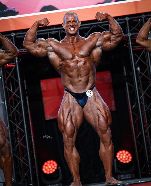 Michal Krizo posing with both arms flexed on a professional bodybuilding stage during an earlier Prague appearance; strong, clean front view of his muscularity without editorial text overlays.