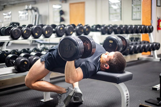 Person performing a controlled dumbbell chest press in a gym, illustrating strength maintenance during weight loss
