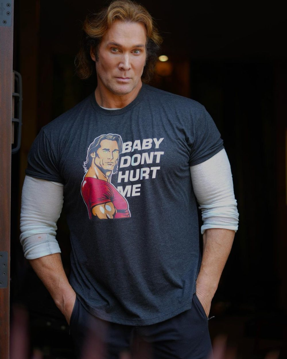 Mike O'Hearn in a gray Baby Don't Hurt Me gym shirt, staring confidently at the camera