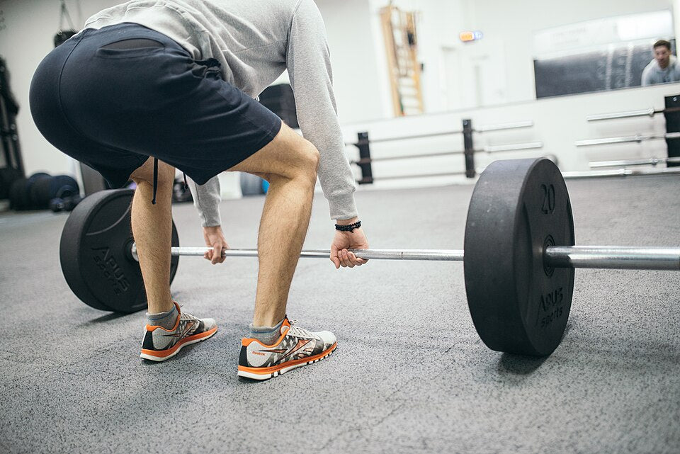 Athlete setting up for a barbell deadlift inside a weight-training gym