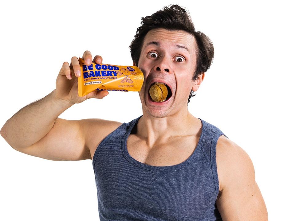 Will Tennyson holding a packaged protein donut snack and tasting one