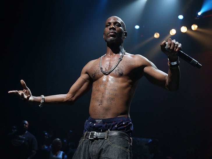 DMX shirtless on a concert stage, holding a microphone with arms extended under dramatic spotlights