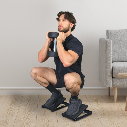 Man holding a dumbbell at his chest while performing a deep heel-elevated goblet squat on two wedges