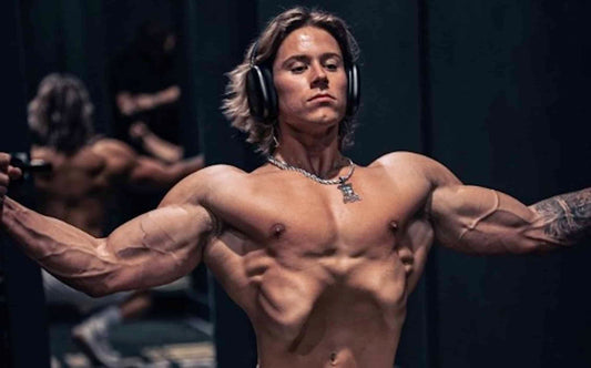 Alex Eubank posing with his arms outstretched during a cable chest exercise in a gym