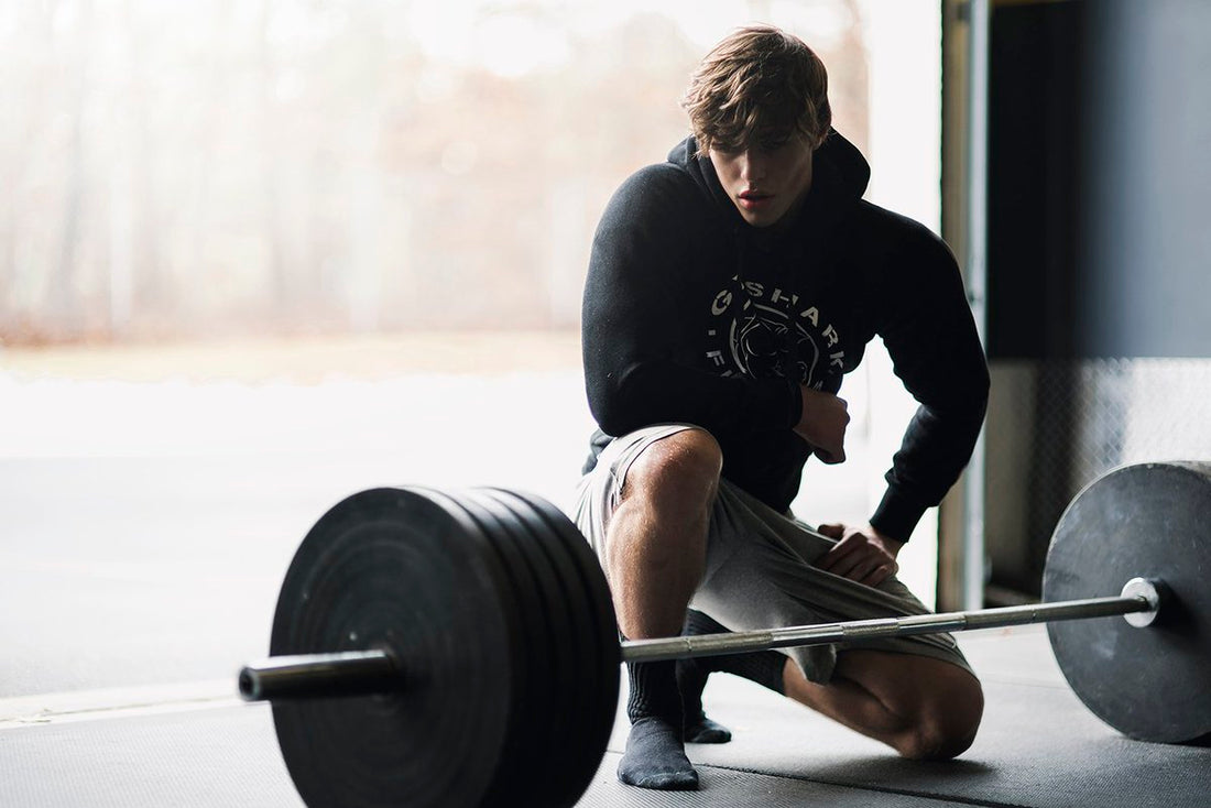 David Laid kneeling beside a loaded barbell on a gym floor