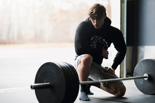 David Laid kneeling beside a loaded barbell on a gym floor