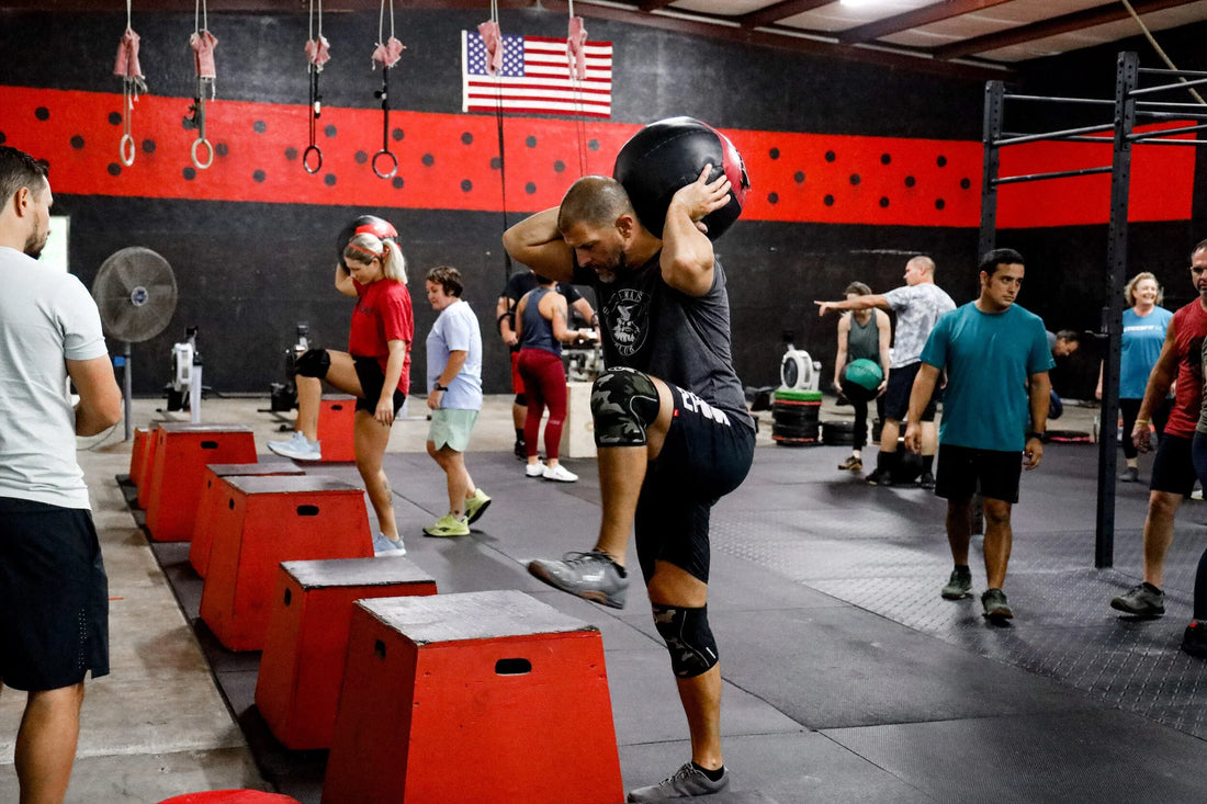 Athlete carrying a medicine ball during a box step-up in a functional fitness class
