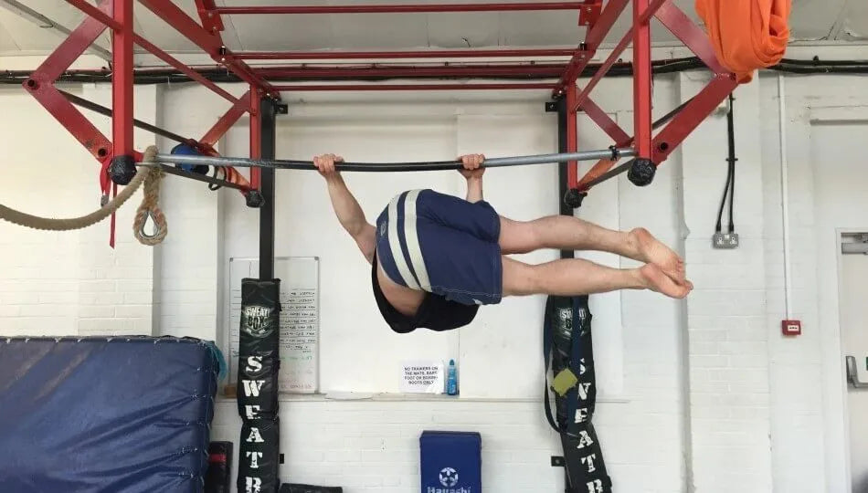 Calisthenics athlete performing a strict hanging windshield wiper with legs extended sideways from a pull-up bar