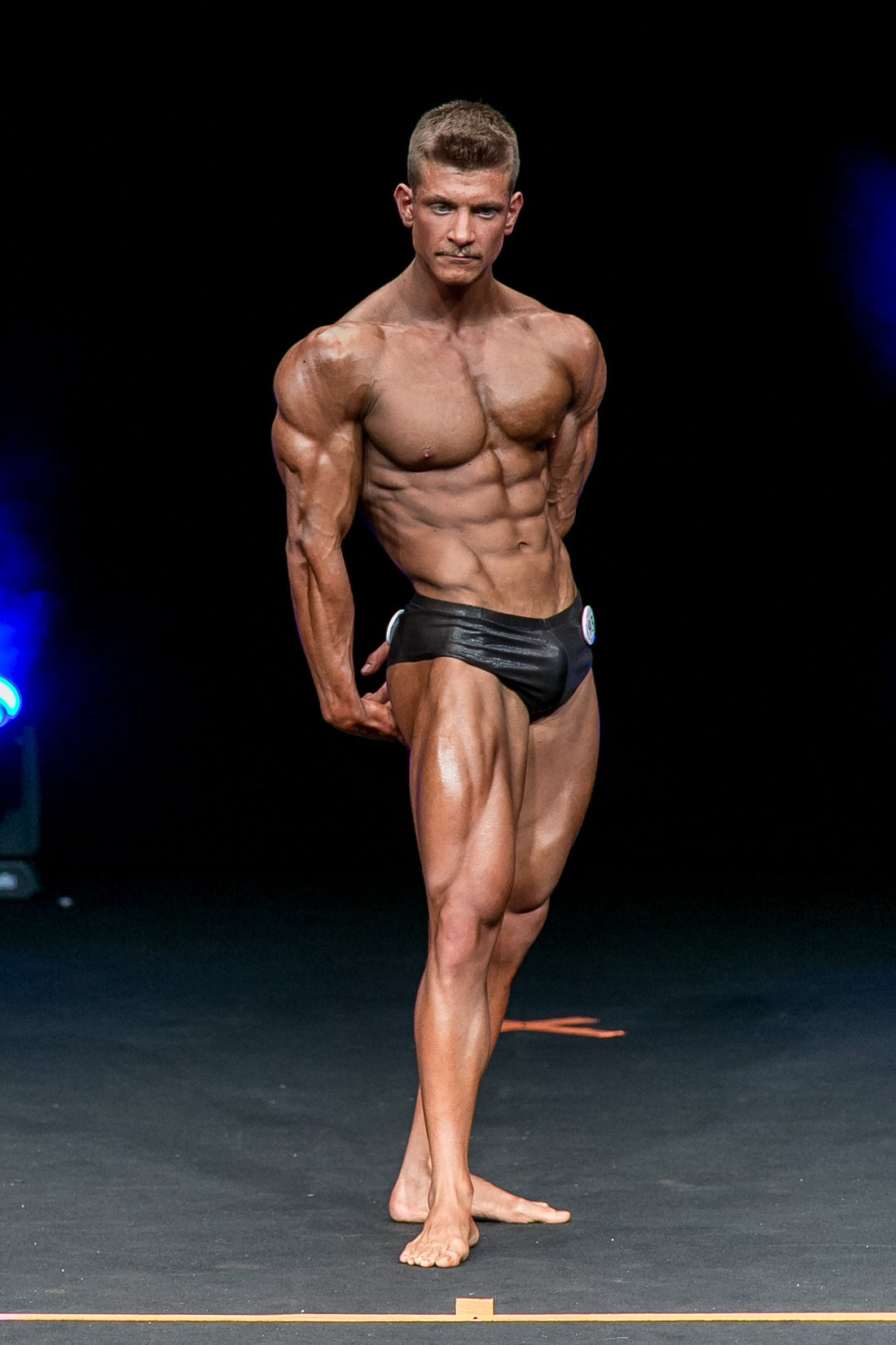 Classic physique competitor displaying balanced muscular proportions on stage