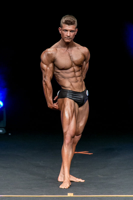 Classic physique competitor displaying balanced muscular proportions on stage