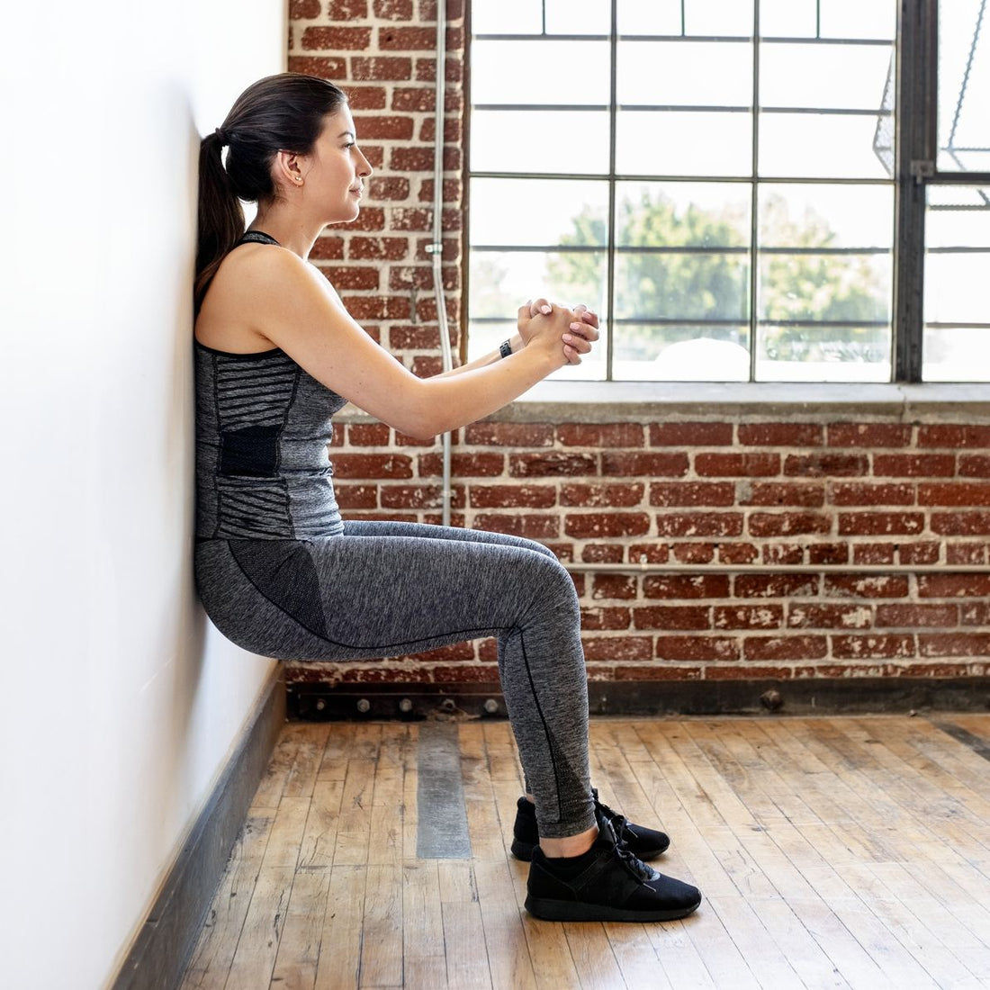 Person performing a controlled wall sit against a gym wall