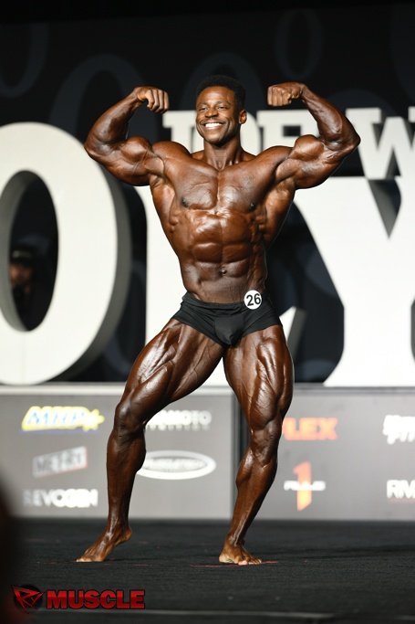 Breon Ansley performing a front double biceps pose in black trunks at the 2018 Olympia